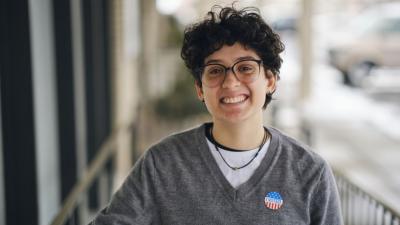 Smiling young Hispanic person wearing an "I Voted" sticker