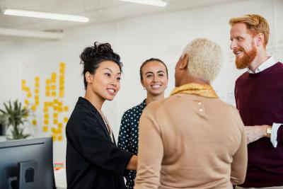 Four diverse colleagues are talking after brainstorming at a meeting.