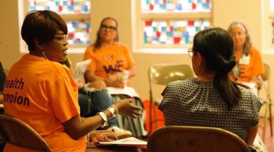 Community health workers discuss education materials in a church with stained glass windows.