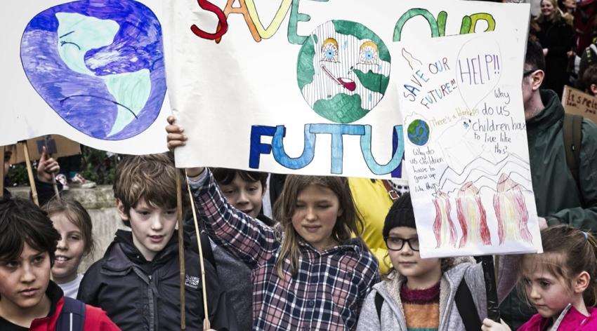 Children at a climate change protest holding signs that say "save our future."